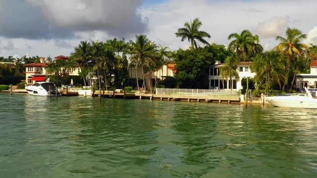 Low aerial or boat pov Miami Beach waterfront mansions and yachts