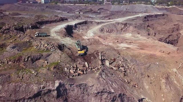 Aerial view of working excavator in the opencast mine. Camera flight over industrial landscape.