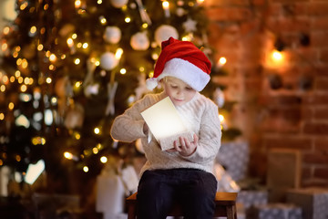 Obraz na płótnie Canvas Cute little boy wearing Santa hat on Christmas eve