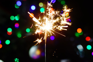 Bright sparkler with Christmas tree on background