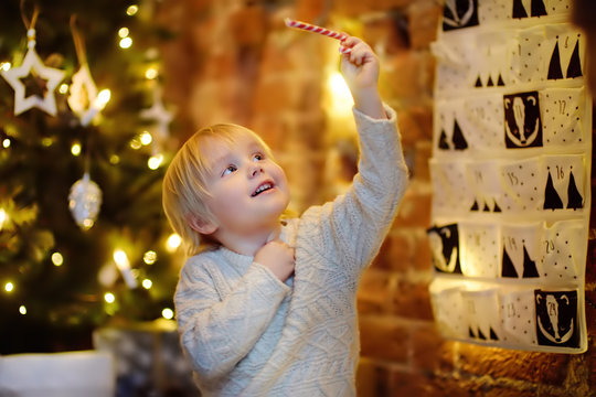 Happy little boy takes last sweet from advent calendar on Christmas eve