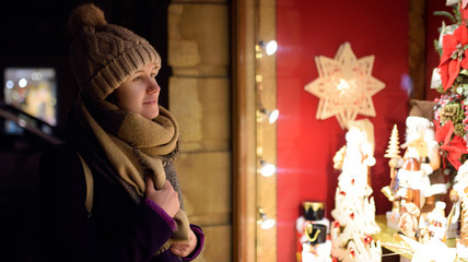 Girl choosing Christmas decorations in shop on winter day