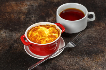 Baked omelet with golden crust in bowl with tea