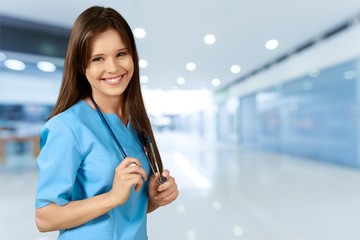 Attractive young female doctor on blurred hospital background