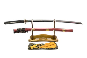 Japanese sword with shiny red scabbard  on wooden stand and silk bag in the front isolated in white...