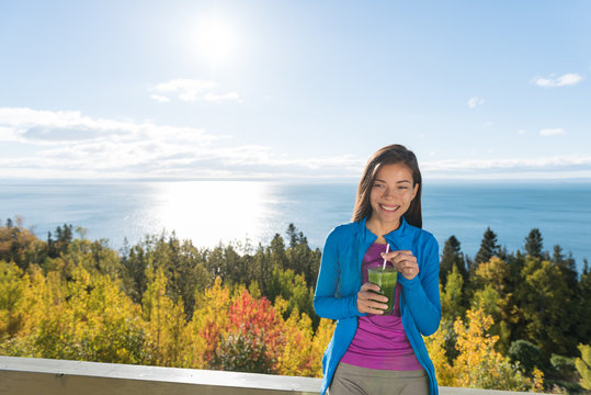 Healthy autumn woman relaxing in outdoor nature drinking green juice smoothie shake as morning breakfast.