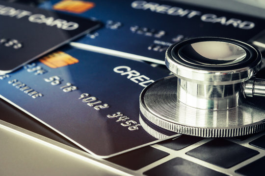 Stethoscope On Mock Up Credit Card With Number On Card At Computer In Hostpital Desk. Health Insurance And Cost Of Medical Care, Self-care During Illness Using Using Payments Card For Medicals Service