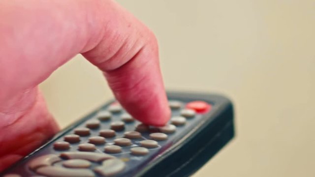 Closeup of male hand pushing remote control buttons