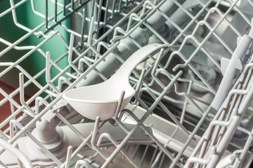 A white plastic cookware lies in the middle compartment of the dishwasher