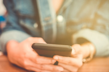 Woman hand using smartphone and laptop with cafe shop sunlight  shade to object beautiful background.