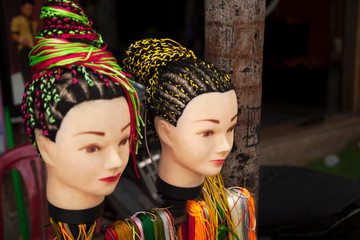 Street hairdresser salon offering braids hairstyle service. Two women heads dummies demonstrating...