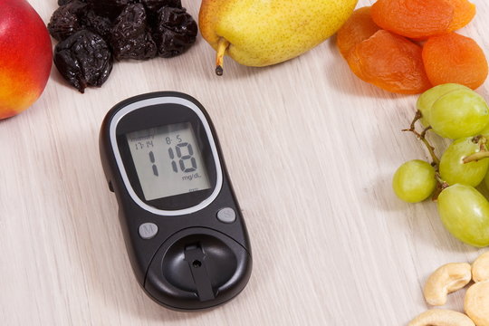 Glucose meter with result of measurement sugar level and healthy fruits, concept of diabetes and healthy nutrition