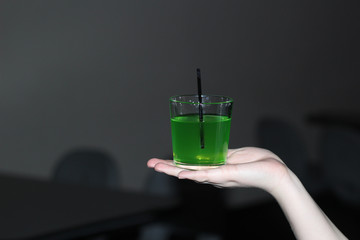a green drink in a transparent glass with a black straw is worth a woman's palm