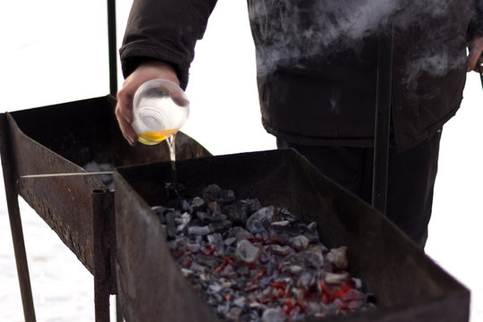 Men's hands are poured into the fire of oil and holds a poker