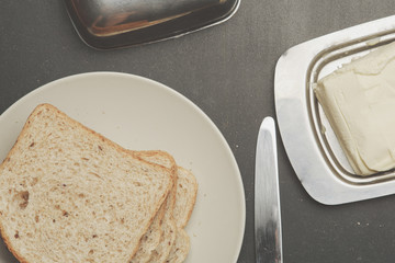 Plate with toasts and butter on dark table