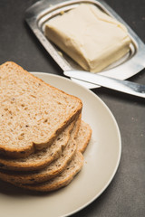 Plate with toasts and butter on dark table
