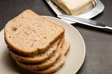 Plate with toasts and butter on dark table