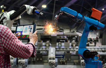 Engineer tablet control the production of factory parts manufacturing industry robots and mechanical arm