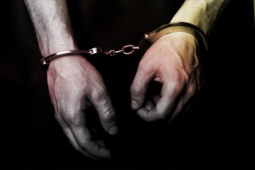 Cropped image of male hands in handcuffs behind his back