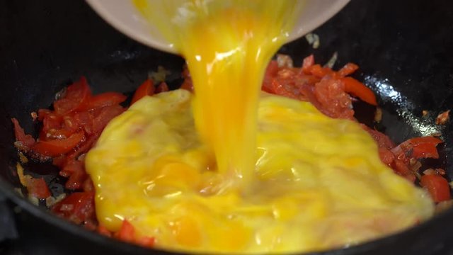 Shakshouka or shakshuka is a North African Jewish origin dish of eggs poached in a sauce of tomatoes, chili peppers and onions, often spiced with cumin. Scrambled eggs with vegetables. Close up