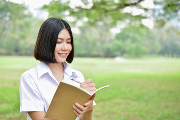 Education Concepts. Beautiful student reading books in the park. Beautiful girl are relaxing in the park. Young student are happy to read. Young student love to study. Education of Asian Women.