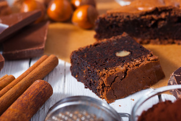 chocolate brownie cake and ingredients, baking papaer on white wood table background
