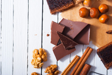chocolate brownie cake and ingredients, baking papaer on white wood table background