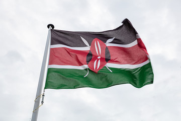 Fototapeta na wymiar Kenya flag on a pole waving, cloudy sky background