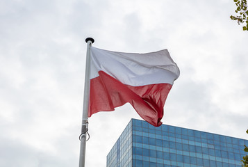 Poland flag on a pole waving, modern office building background