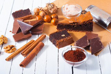 chocolate brownie cake and ingredients, baking papaer on white wood table background