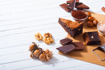 chocolate brownie cake and ingredients, baking papaer on white wood table background