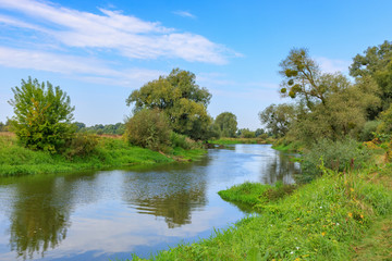 Fototapeta na wymiar View of small river against blue sky in autumn morning. River landscape