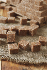 cataract of brown sugar cubes on wooden background