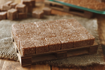 golden pyramid of brown sugar cubes on wooden background