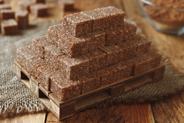 golden pyramid of brown sugar cubes on wooden background