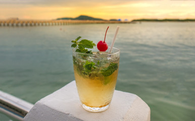 Mojito cocktail drink with evening sunset on beach background