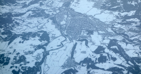 Aerial view of a town from an airplane in the Alps all covered by snow