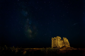 Nightscape with milky way and shooting star and an old ruin of a tower as foreground.