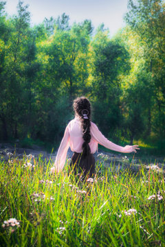 Young girl in summer sunny day walking and dancing in fields flowers
