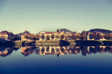 Fototapeta na wymiar Im Fluss spiegelnde Wohnhäuser im Herbst, Farben