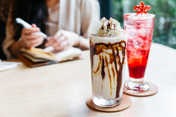 Caramel milkshake topping with whip cream and chocolate powder and strawberry Italian soda.