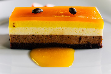 Layer cake including orange sauce and chocolate topping with coffee seed and served with fresh sliced strawberry. 