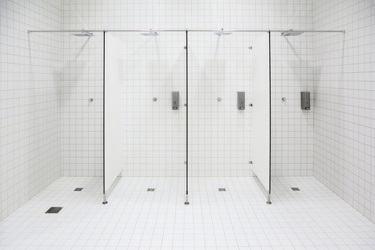 Public shower in spa center. White ceramic tiles on wall and floor.