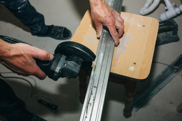 Man is holding in his hands and angle grinder. Renovation repairing maintenance works indoors in the flat.