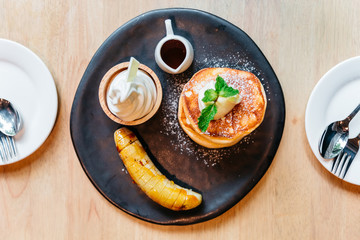 Top view of Fluffy pancakes served with caramel banana, ice cream and syrup.