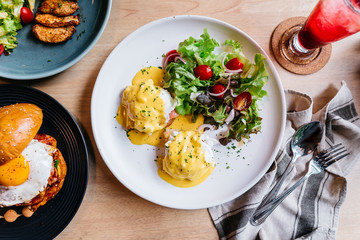 Top view of Egg benedict served with salad in white plate on wooden table for delicious breakfast and brunch.