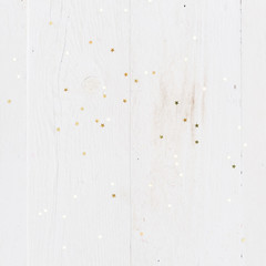 Obraz premium Closeup of golden stars confetti on vintage white wooden background. Winter, Christmas celebration, holidays season concept