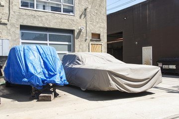 A view of two vintage cars with a cover in the street in Venice, California