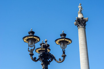 Fototapeta na wymiar Low angle view of street lights and the iconic Nelson's Column against a clear blue sky at Trafalgar Square, London
