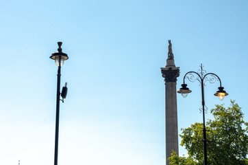 Fototapeta na wymiar Side view of Nelson's Column and street lights against a summer sky at Trafalgar Square in London, England